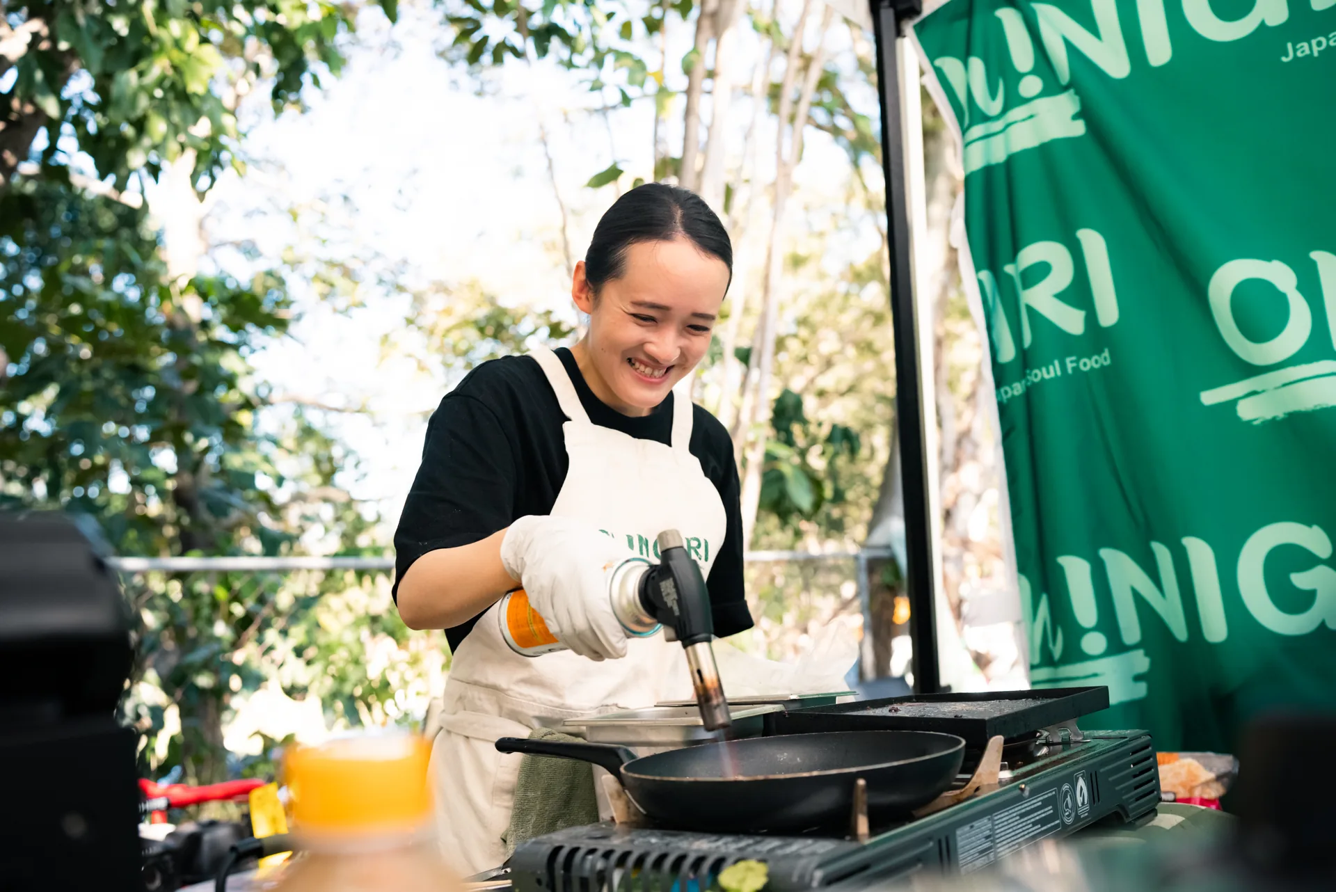 Oh!NIGIRI team member cooking with a smile at the market stall