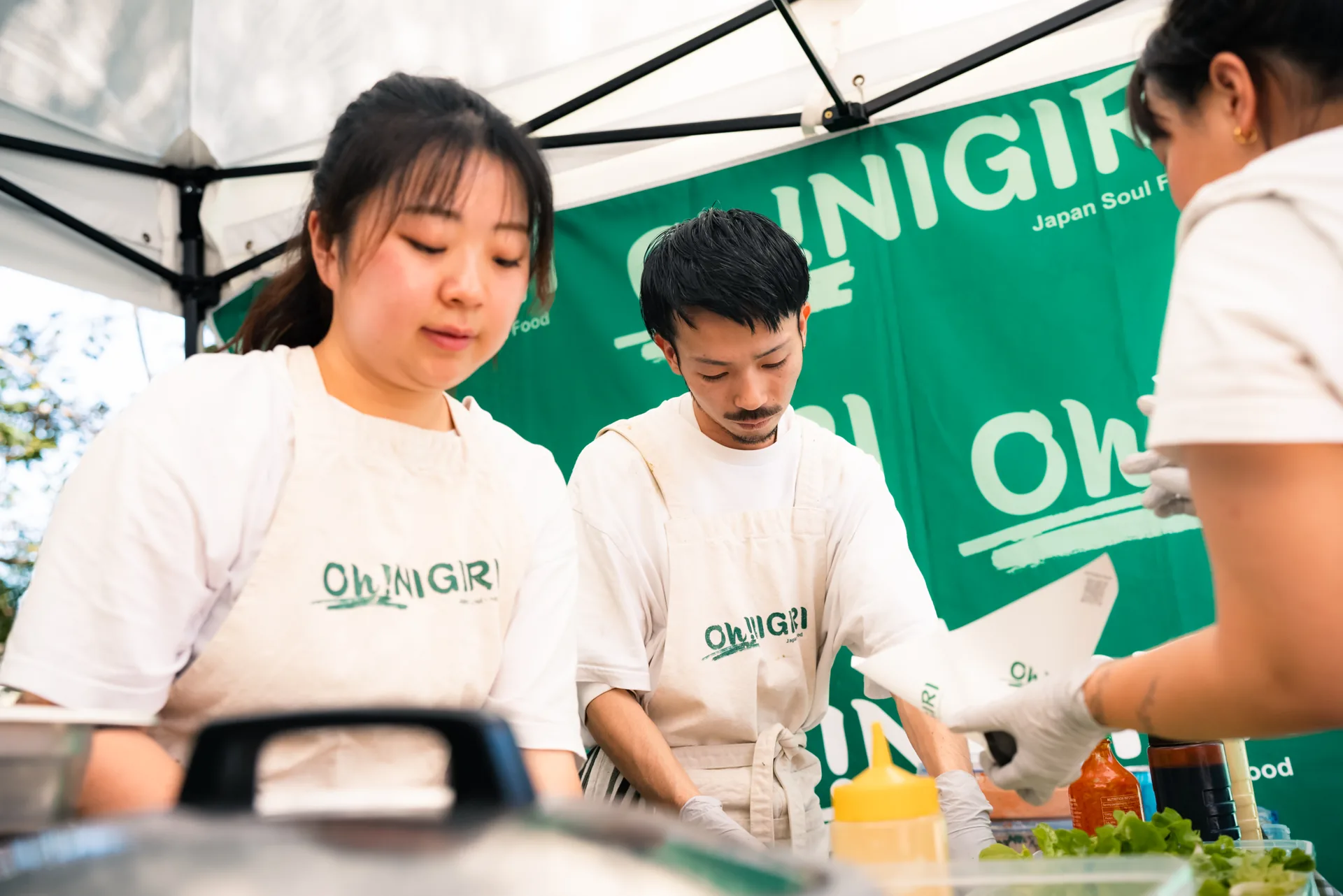Three Oh!NIGIRI team members preparing orders inside the branded stall