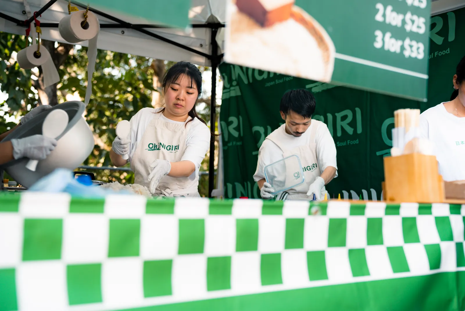 Oh!NIGIRI team preparing food behind the green market counter