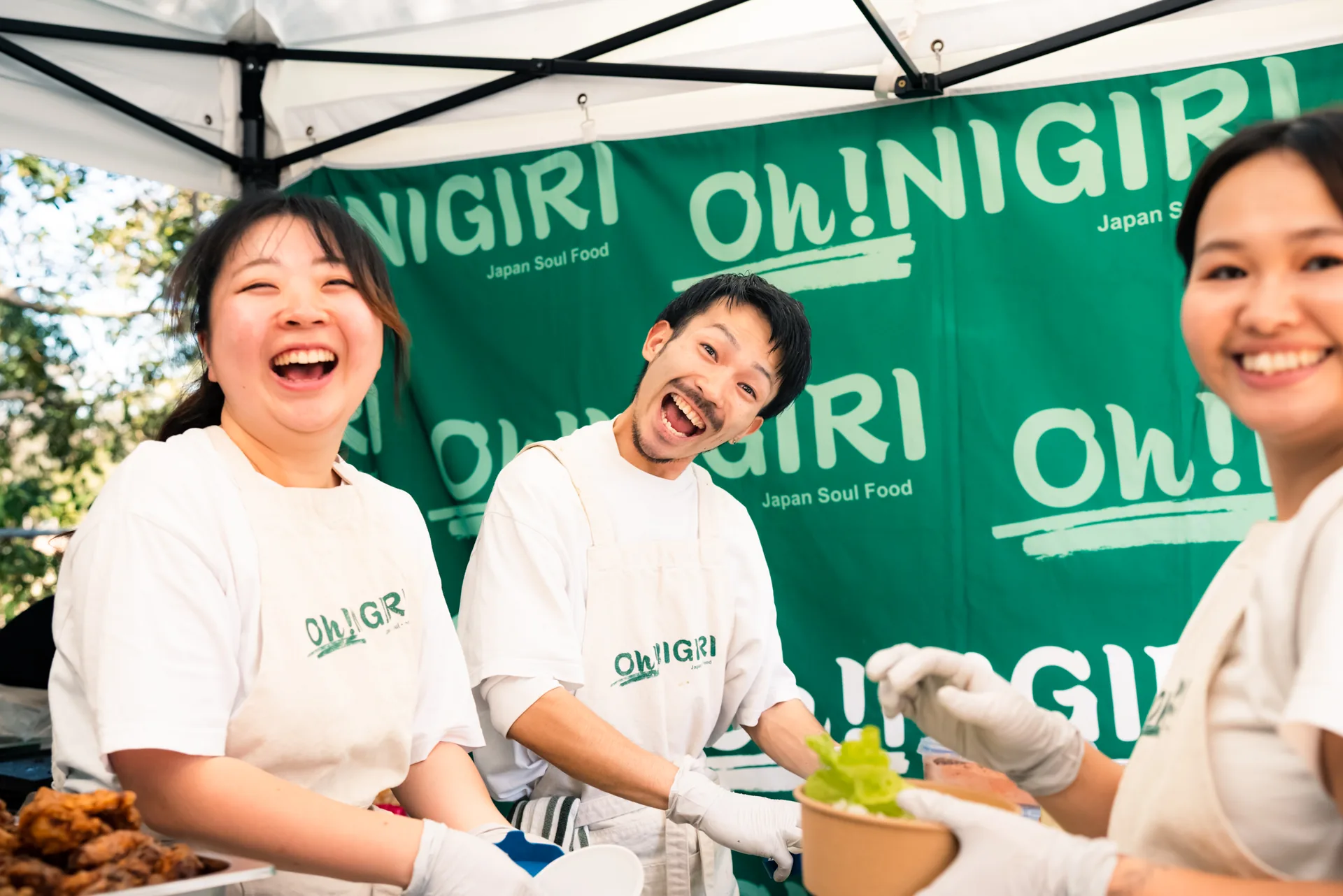 Oh!NIGIRI team smiling together inside the branded market stall